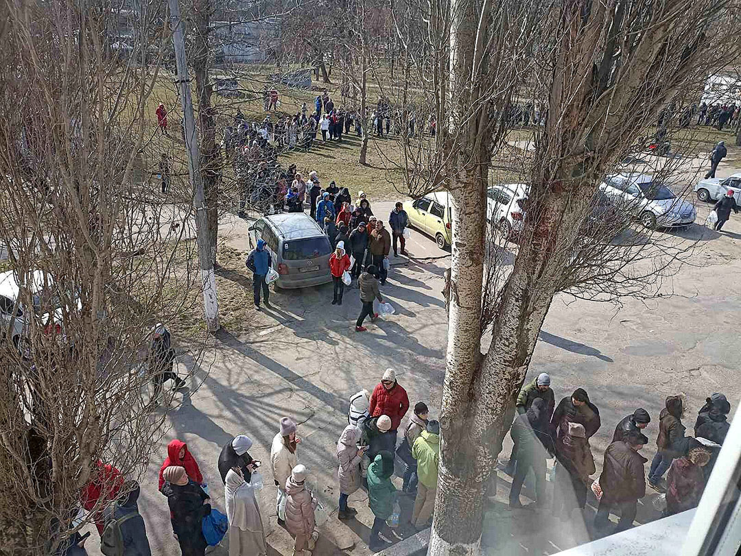 Queues of people line up to collect food in the local village of Bilozerka distributed by the church. Photo: Chris McCullough